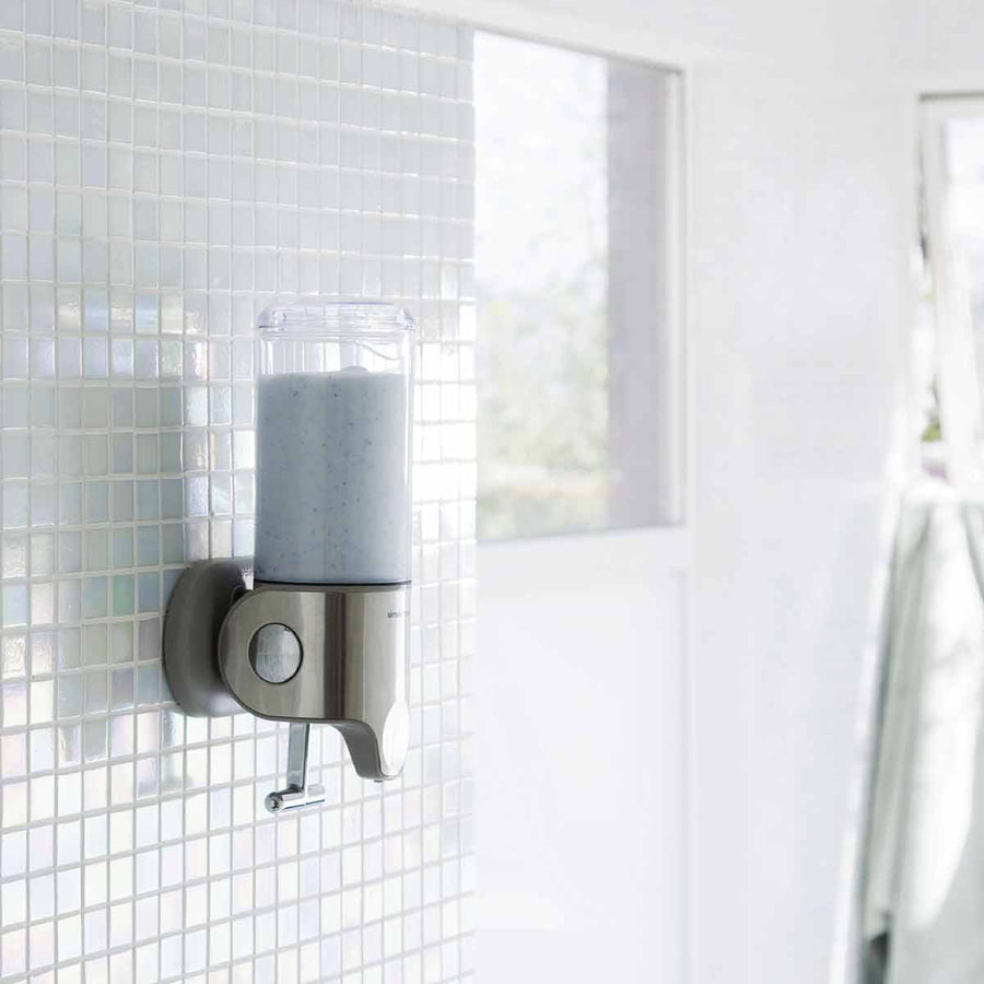 Angled view of Simplehuman Single Wall Mount Pump in Brushed Stainless Steel, space-saving shower dispenser