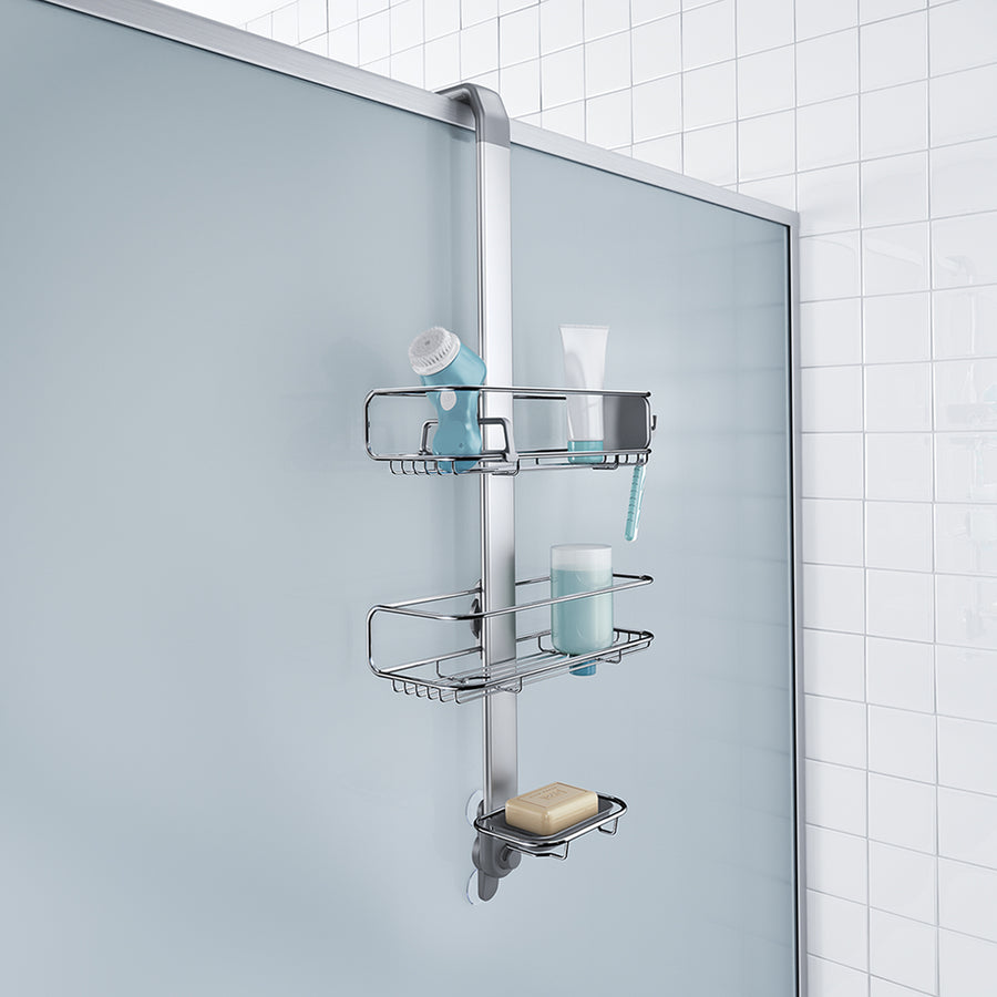 Lifestyle view of Simplehuman Polished Stainless Steel Adjustable Shower Caddy over shower door, secure hanging design with stabilizing suction cup.