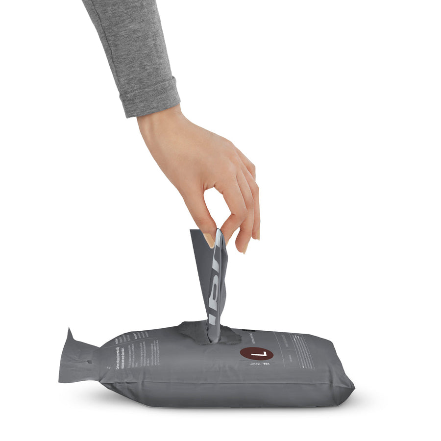 Usage view of Simplehuman Code L Odorsorb Liners, hand pulling a single bag from the gray refill pack.
