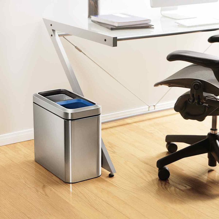 Lifestyle shot of Simplehuman Brushed Stainless Steel 20L Dual Compartment Slim Open Can under an office desk, space-saving recycling.