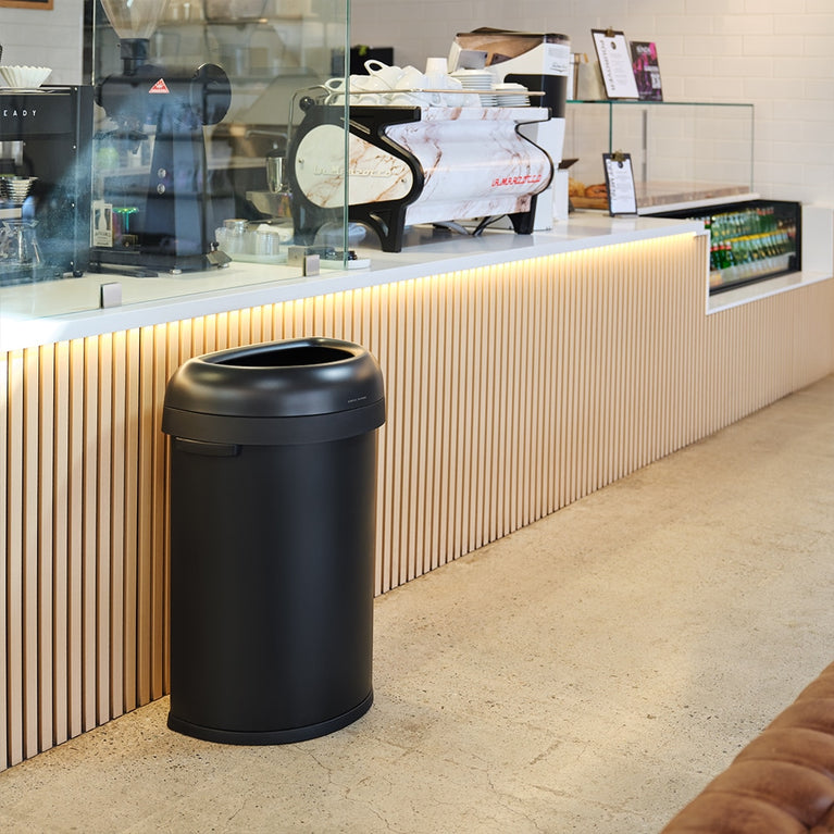 Simplehuman's Matte Black Semi-Round Open can in a modern cafe setting. 